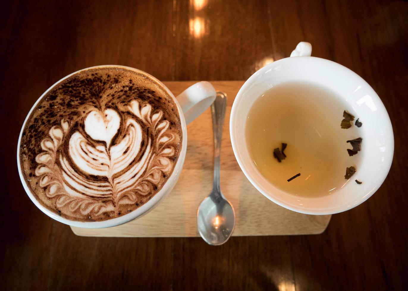 Cappuccino with fresh milk foam and latte art in a white ceramic glass on a wooden table at a coffee shop. photo