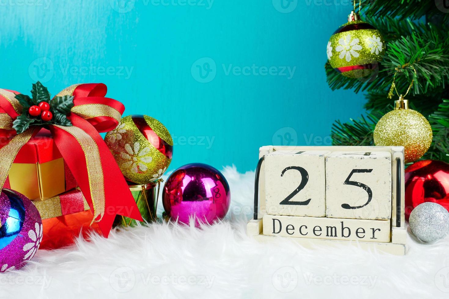 tema del día de navidad con decoración y caja de regalo calendario de bloque de cubo de madera fecha actual 25 y mes diciembre copia espacio para texto. celebración navidad y x'mas concept.on fondo verde foto