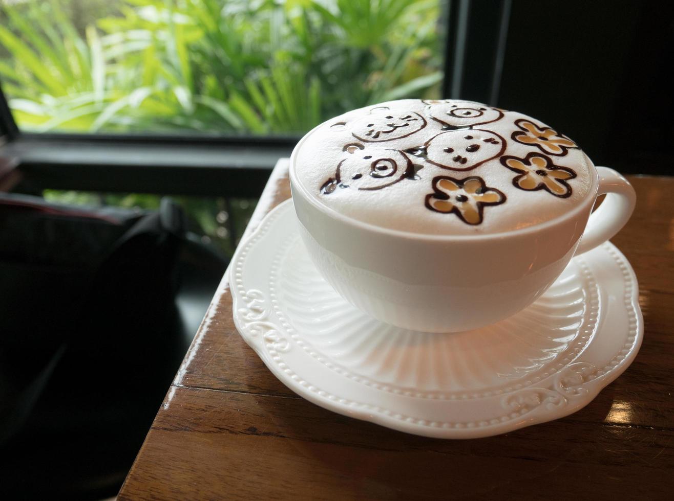 Cappuccino with fresh milk foam and latte art in a white ceramic glass on a wooden table at a coffee shop. photo