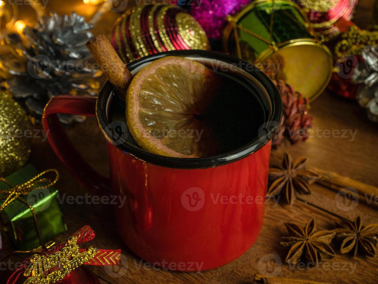 Hot drink alcohol,Mulled red wine in red rustic mugs spices cinnamon stick and citrus fruit.decoratied fir festive on wood table.Celebration christmas and Happy New Year Concept. photo