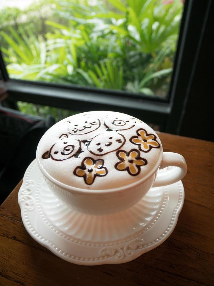 Cappuccino with fresh milk foam and latte art in a white ceramic glass on a wooden table at a coffee shop. photo