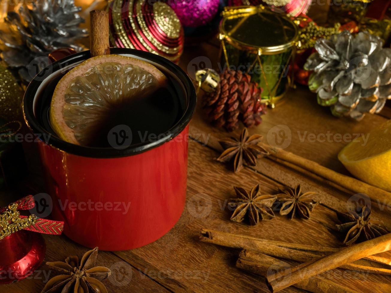 Hot drink alcohol,Mulled red wine in red rustic mugs spices cinnamon stick and citrus fruit.decoratied fir festive on wood table.Celebration christmas and Happy New Year Concept. photo