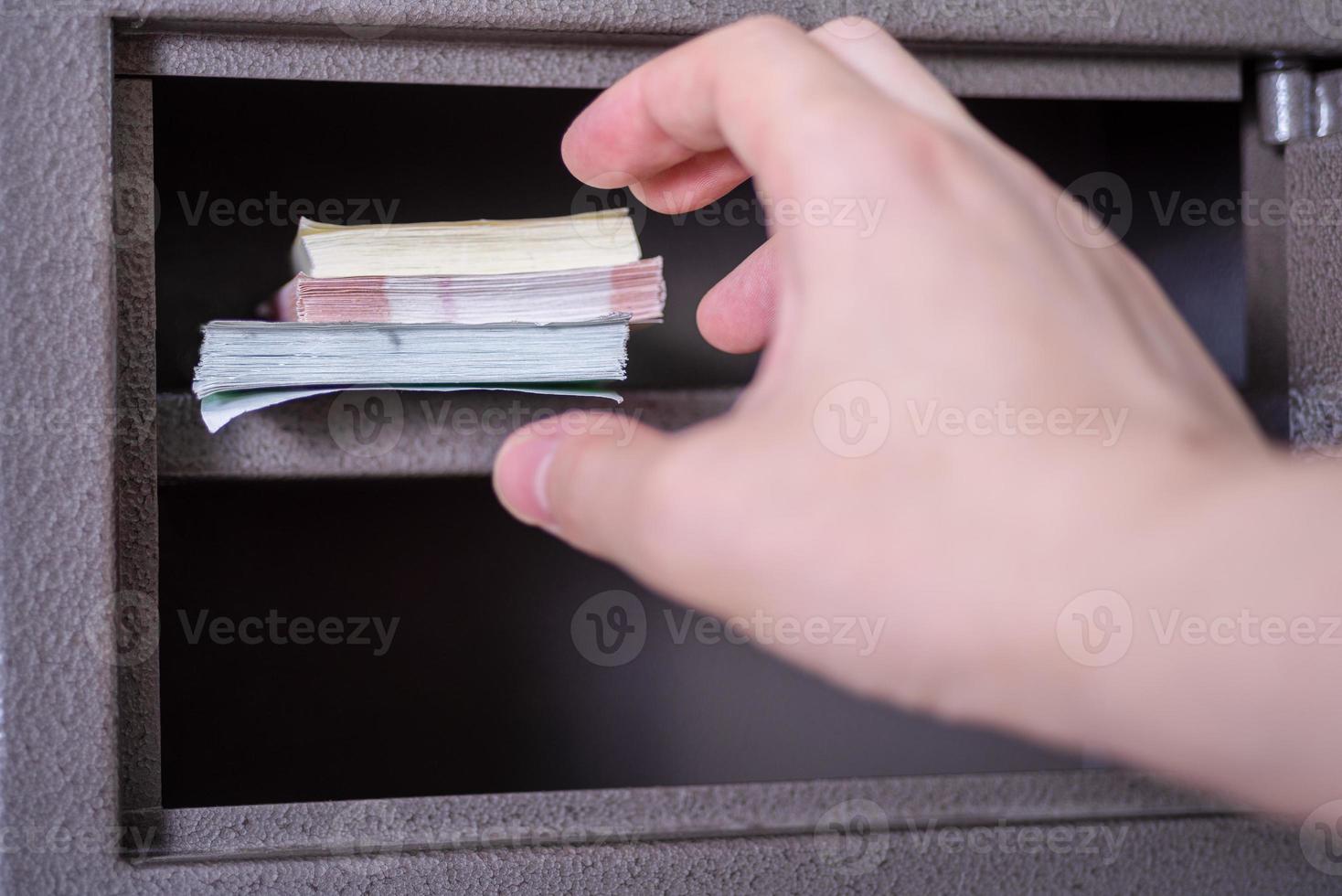 el dinero está en la caja fuerte, la mano toma o roba el dinero en la caja fuerte. foto