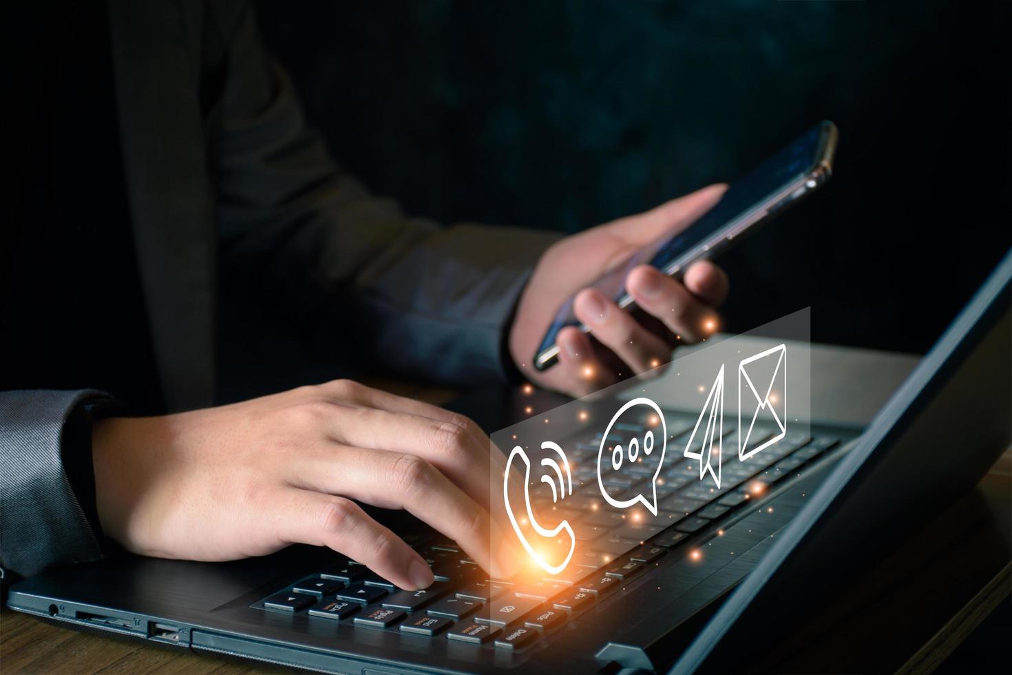Concept of business communication. Businessman using computer and smartphone to contact customers via online internet, meeting, global network, shape icon phone email mail message on virtual screen. photo