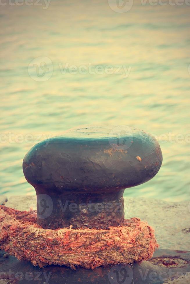 Iron pier with a big rope. Vintage style. Vertical image. photo