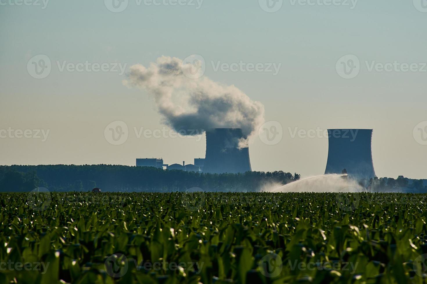 silueta de una central nuclear -fumar- en francia con un campo verde delante foto