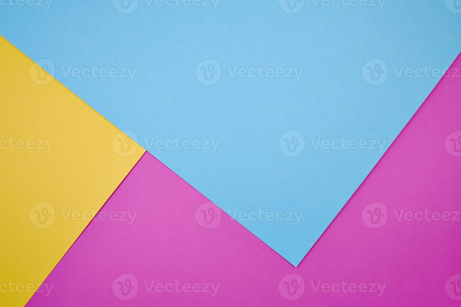 blue, magenta and yellow colored papers laid frame filling as background photo
