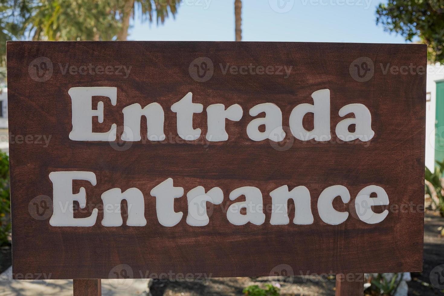 la palabra española -entrada- significa entrada en inglés, ambas escritas aquí en un cartel de madera marrón foto