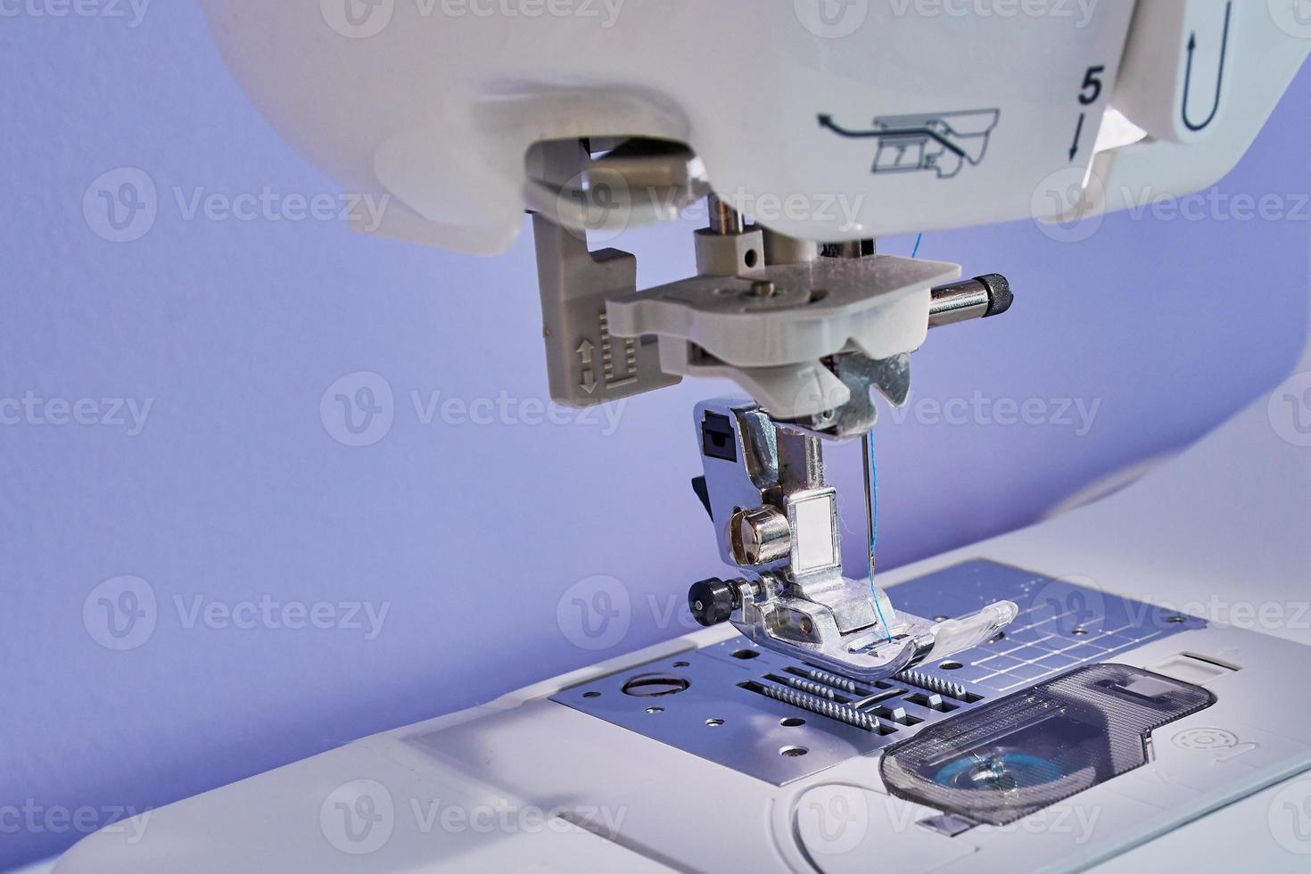 macro color picture of a sewing foot of a white sewing machine, violet wall background photo