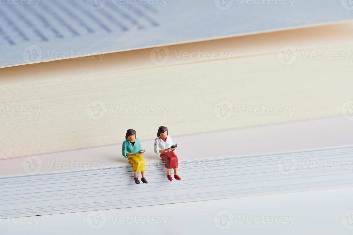 two miniature people reading books photo