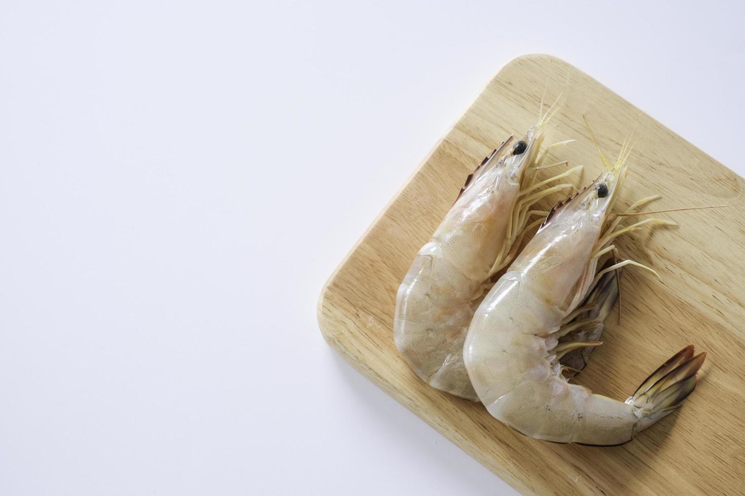 camarones de patas blancas, camarones blancos del Pacífico, langostinos, penaeus vannamei sobre tabla de cortar de madera aislada sobre fondo blanco. foto