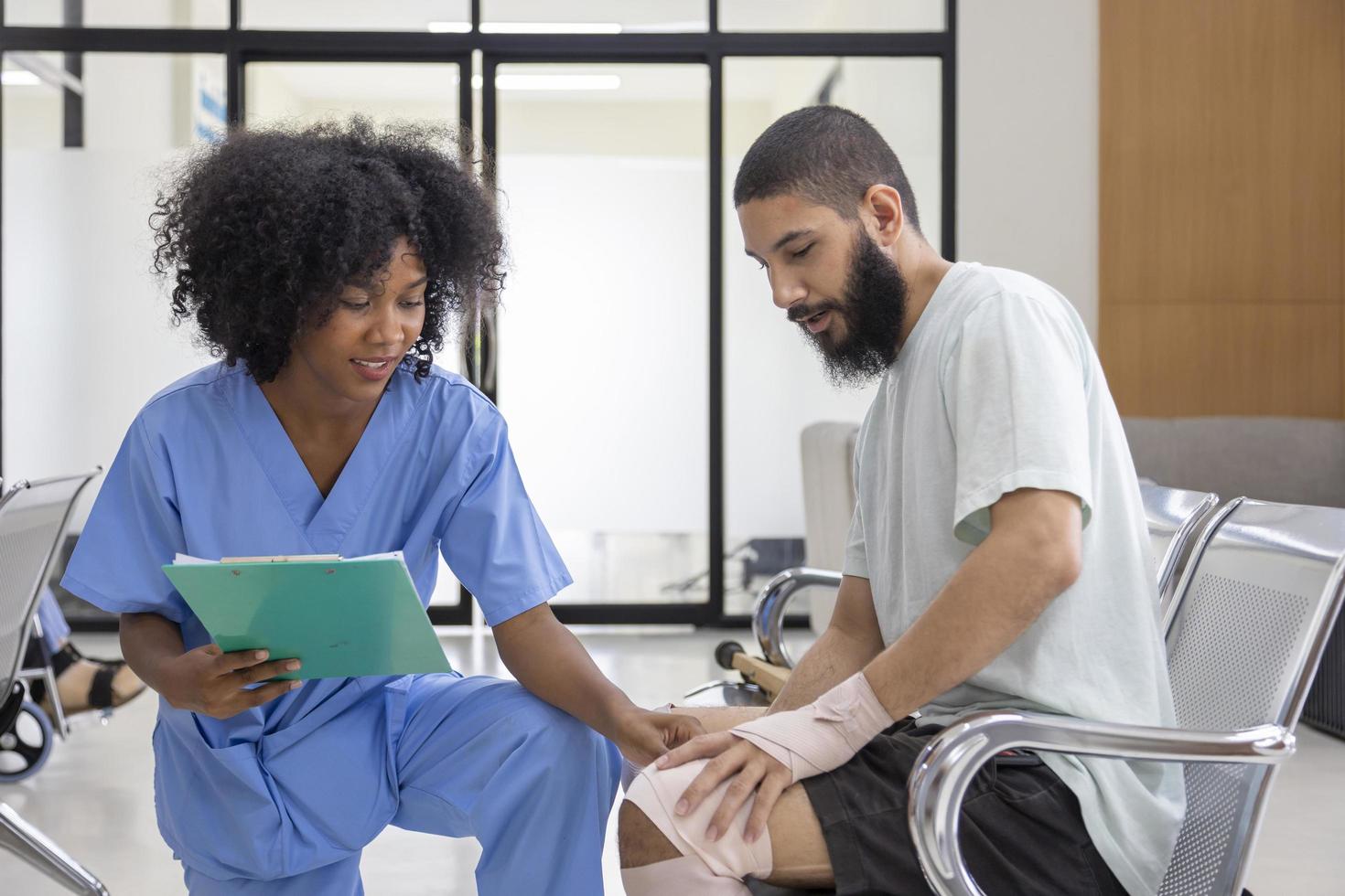 una enfermera africana está examinando la tendinitis en una lesión de rodilla por un accidente deportivo en un paciente de oriente medio para el proceso de tratamiento y rehabilitación foto