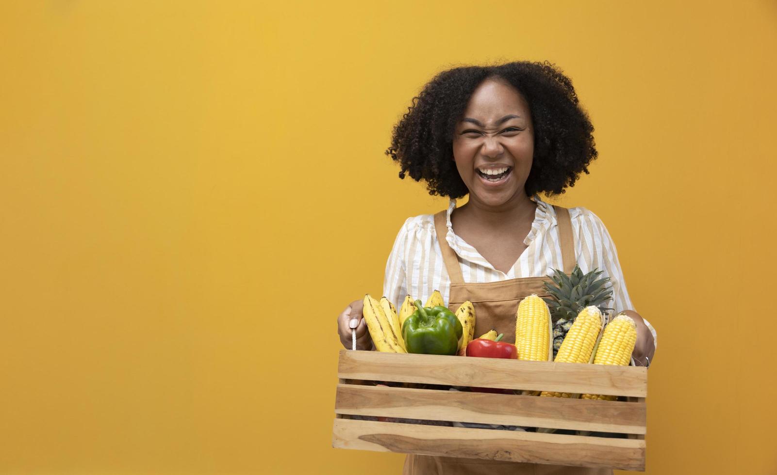 entrega feliz de una mujer afroamericana que lleva un carro lleno de productos orgánicos tropicales de cosecha propia del jardín local para ingredientes veganos y vegetarianos foto