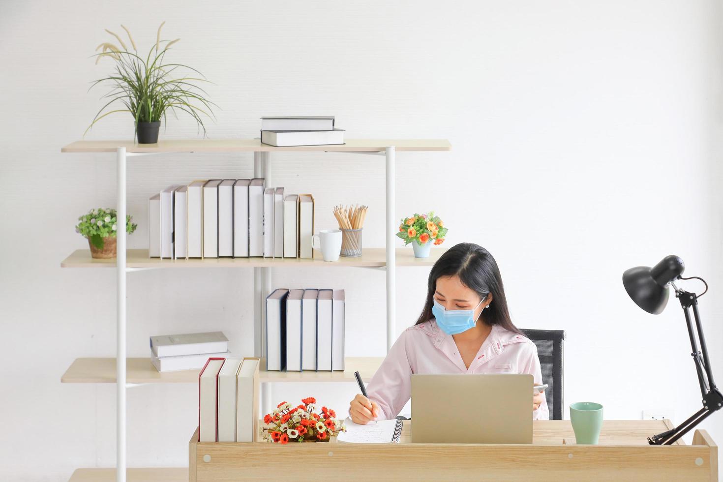 Female employee wearing medical facial mask working from home office as social distancing policy in the business office during new normal change after coronavirus or post covid-19 pandemic situation photo