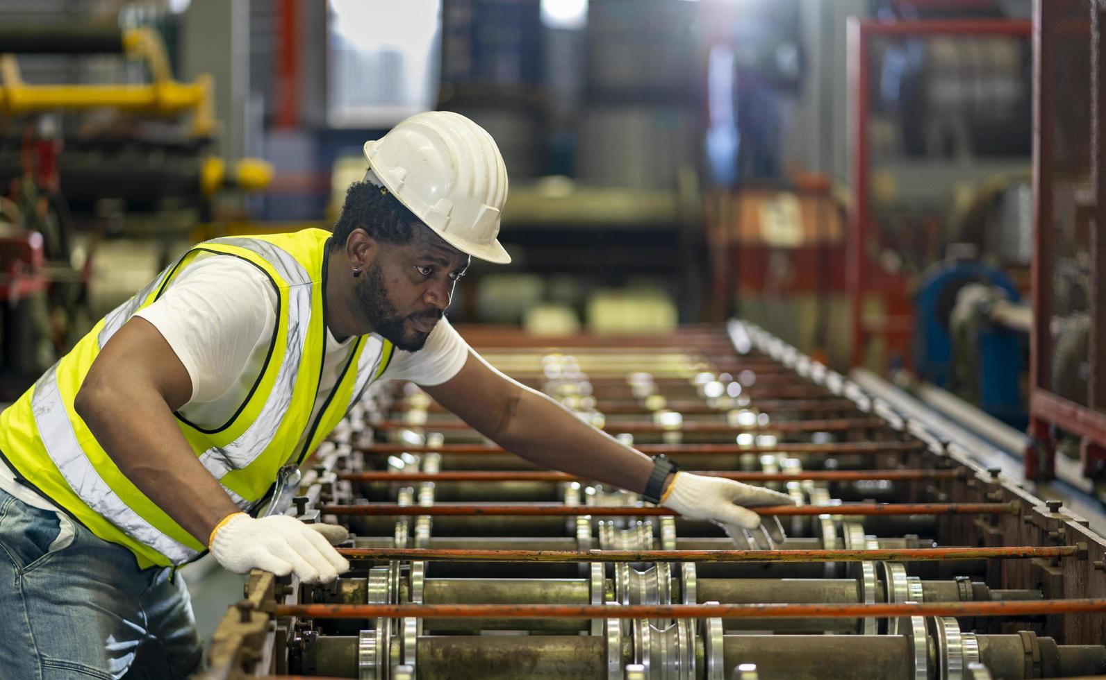 African American industrial worker is checking the setup value of metal sheet roll forming machine inside roof factory for safety industry construction concept photo