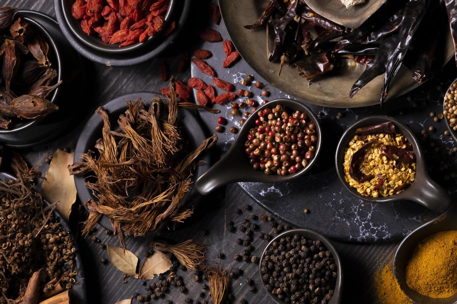 Various type of oriental earthy flavor dry spices on dark wooden table such as turmeric, black pepper, chili flake, bay leaf, for medicinal and herbal use in healing and cooking usage photo