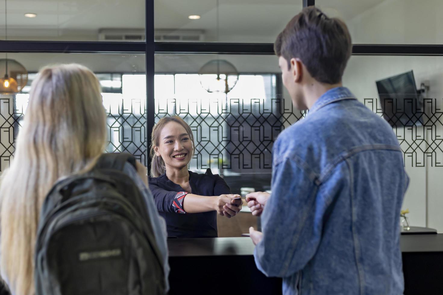 Caucasian tourist couple is handing passport to the reception at hotel lobby counter for check in to the room for international travel and vacation concept photo