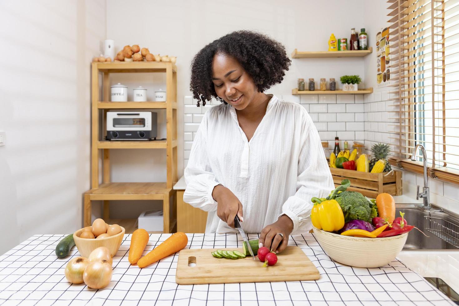 African American housewife is chopping organic cucumber to prepare simple and easy southern style salad meal for vegan and vegetarian food concept photo