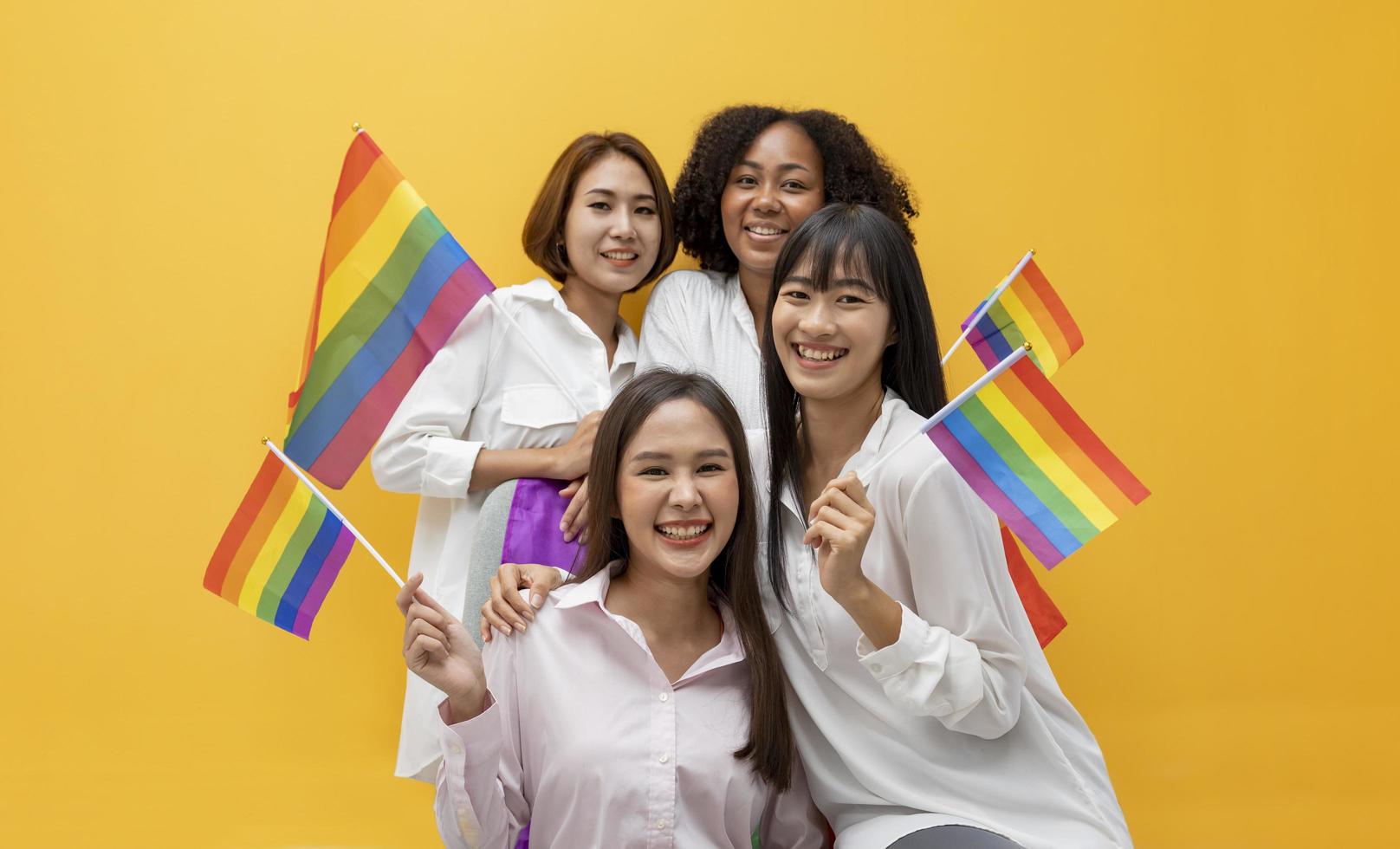 Group of diversity woman friends waving LGBTQ rainbow flag for pride month to promote equality and differences of homosexual and discrimination concept photo