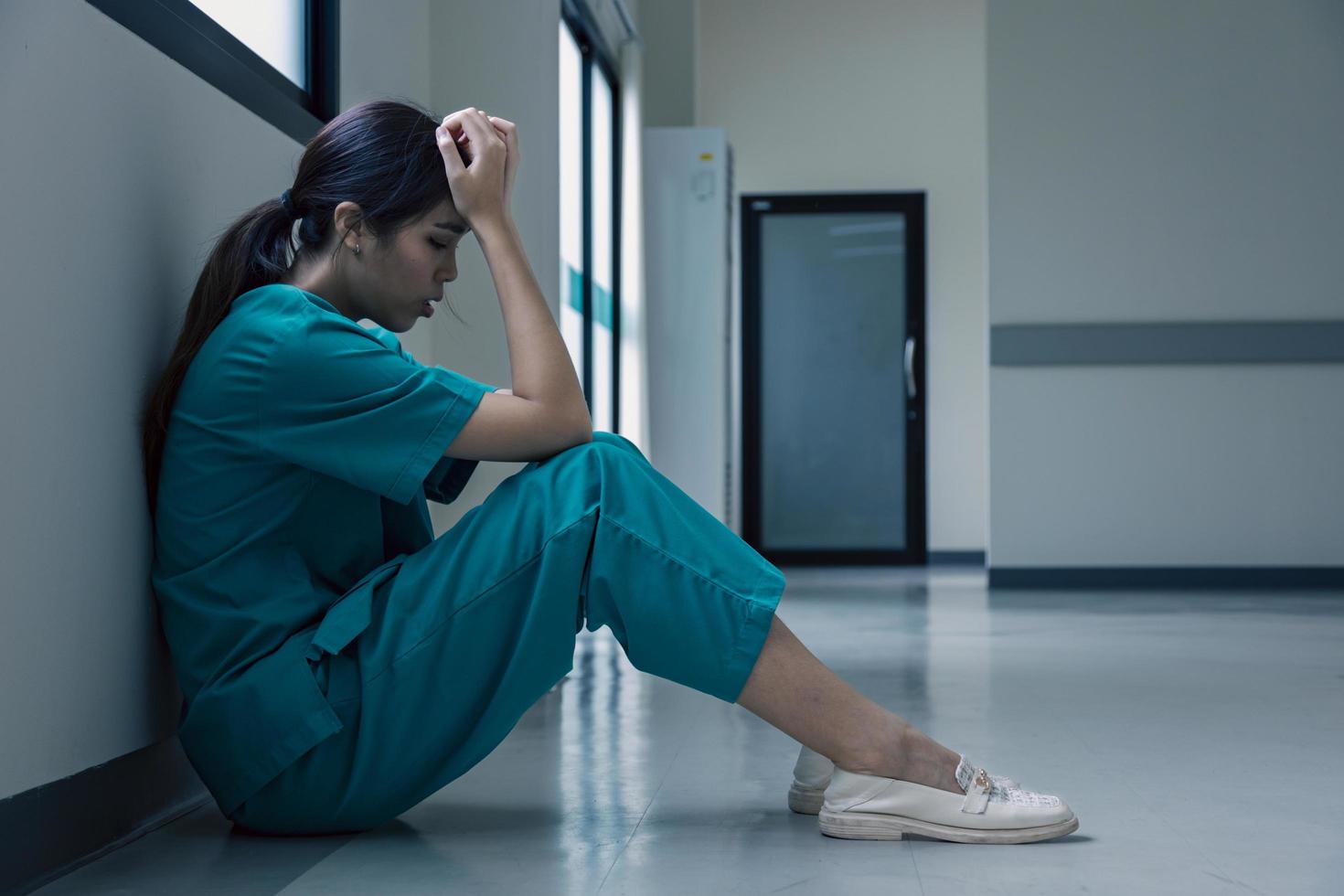 Medical nurse is sitting down on floor in frustration and grief after failure of patient body condition photo
