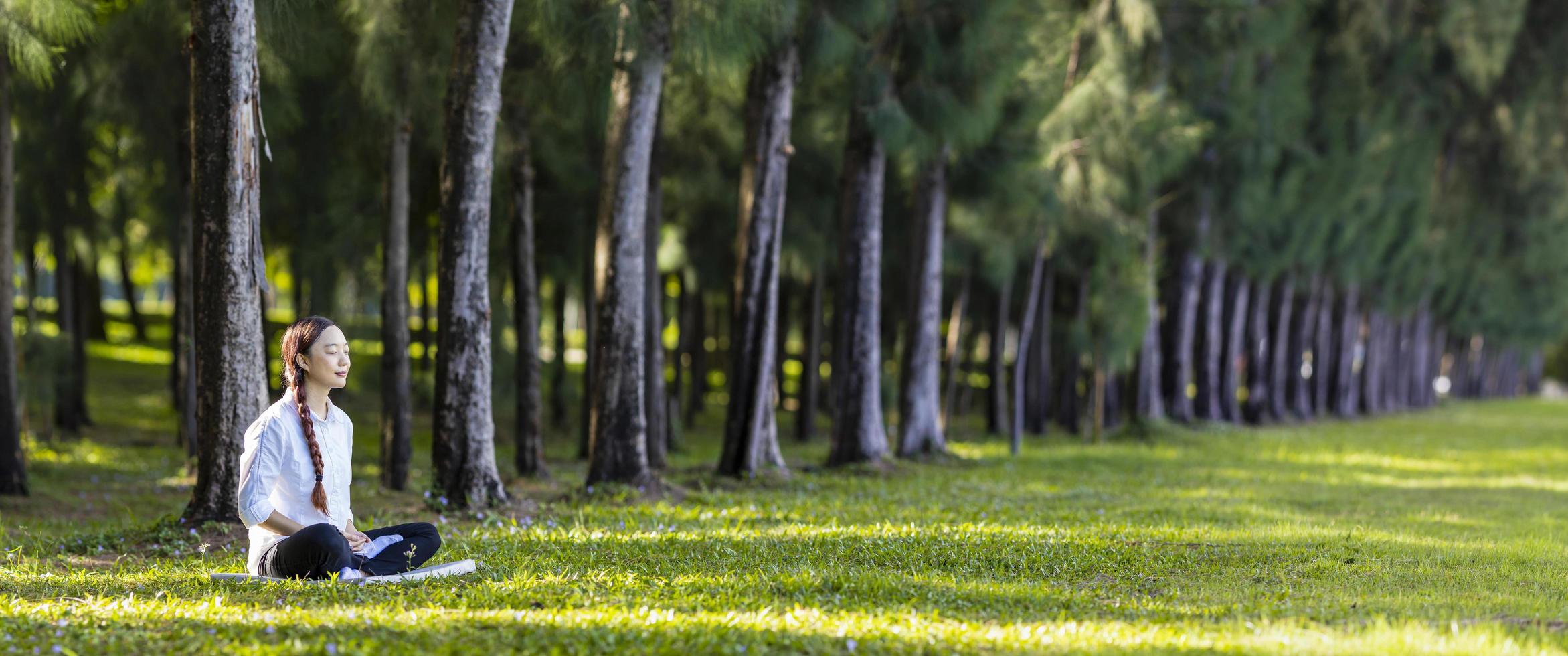 Woman relaxingly practicing meditation in the pine forest to attain happiness from inner peace wisdom for healthy mind and soul concept photo