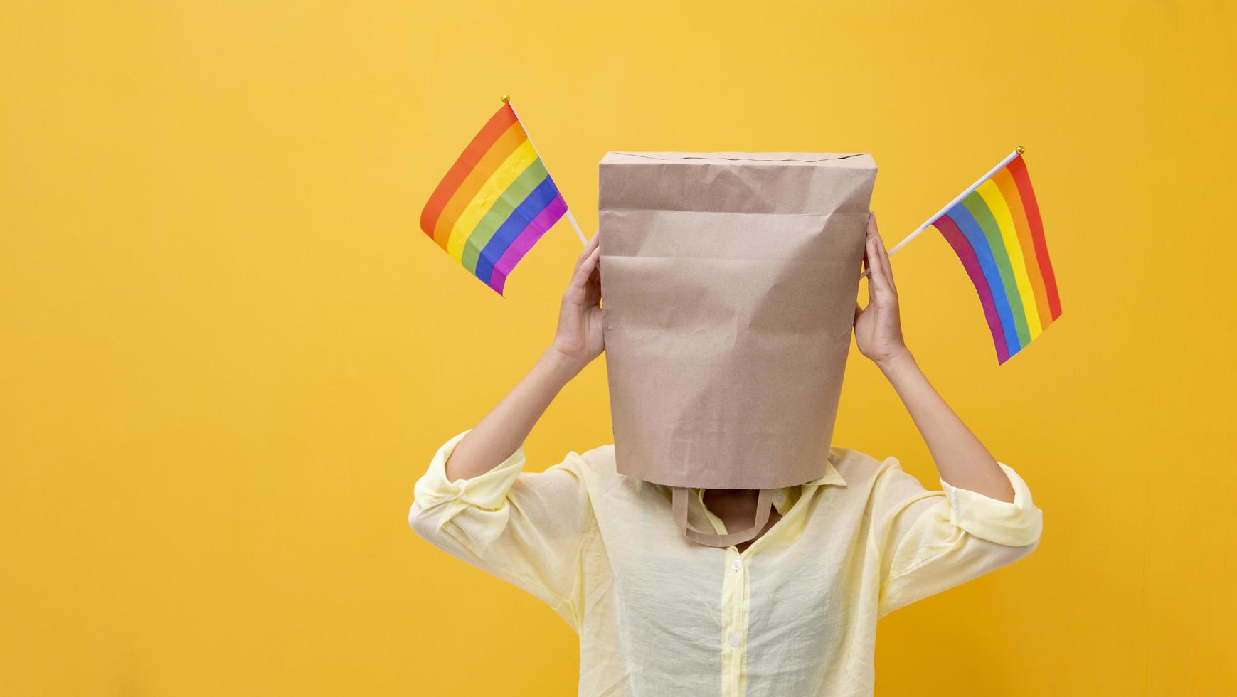 Portrait of shy LGBTQ people covering her face waving rainbow flag for coming out of the closet in pride month to promote marriage equality and differences of homosexual and discrimination concept photo