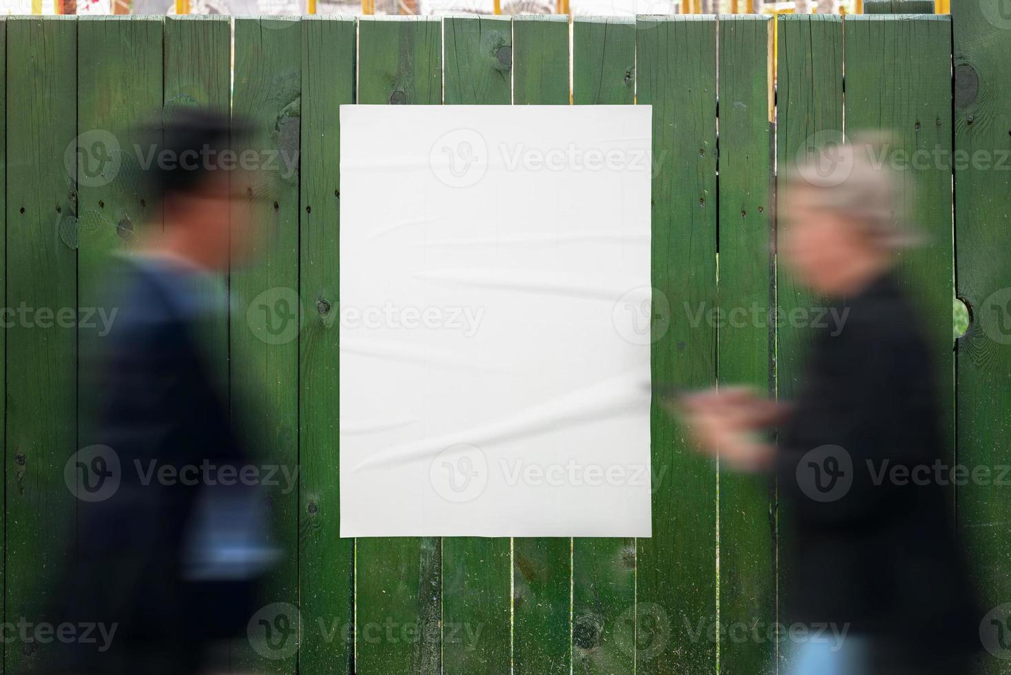 Poster mockup on a green wooden fence. People pass by the poster. Blank poster for design presentation photo
