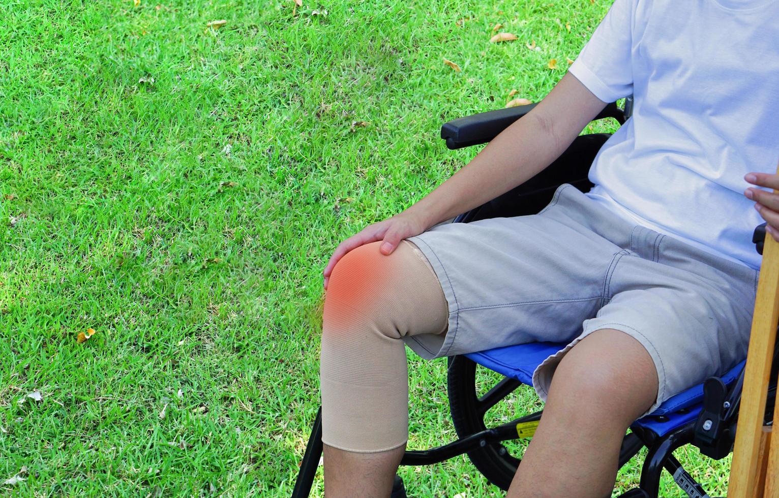 Knee injury patients sitting on a wheelchair in a park or lawn. Healthcare and medical concept. photo