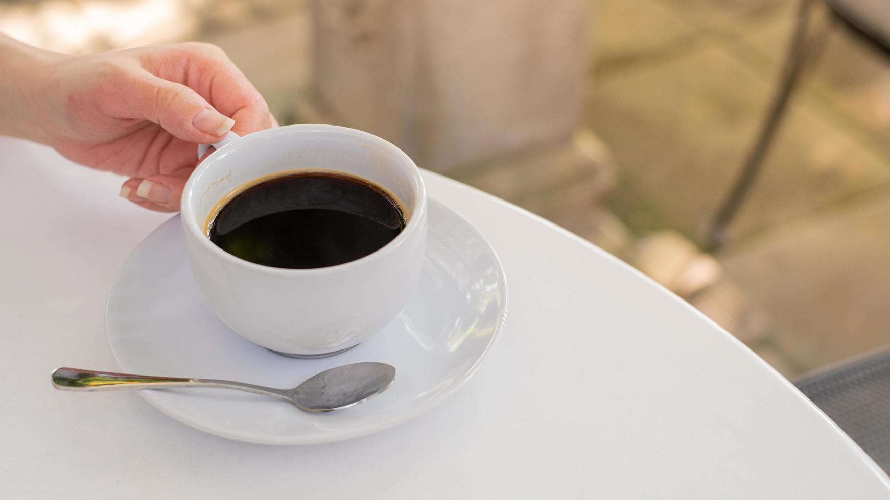 una taza de café en una mesa blanca con tiempo de descanso, concepto de comida. primer plano de un vaso de refresco de mezcla de espresso caliente con espacio de copia foto