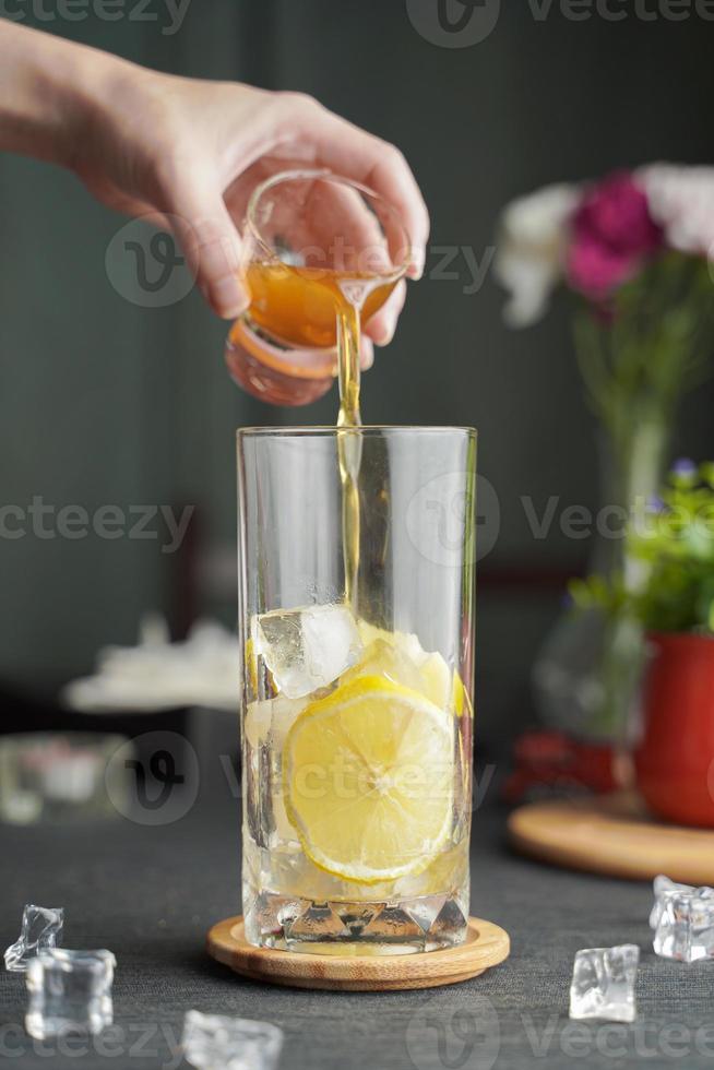 Glass of espresso with lemon juice and fresh sliced lemon on wooden table and copy space, Summer Cocktail, Cold brew coffee or black tea. photo