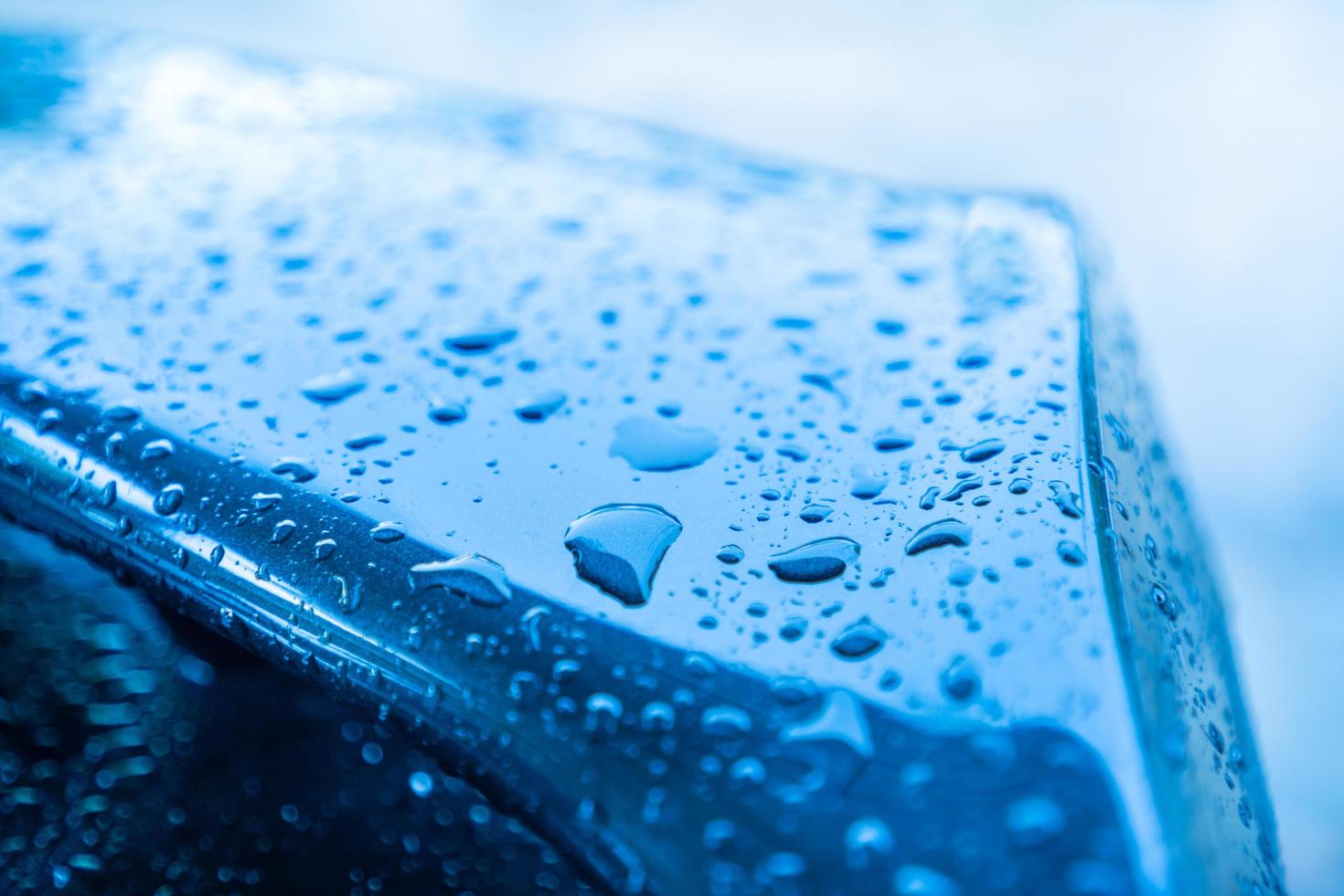 Raindrops on the black car body on a rainy day in the evening photo