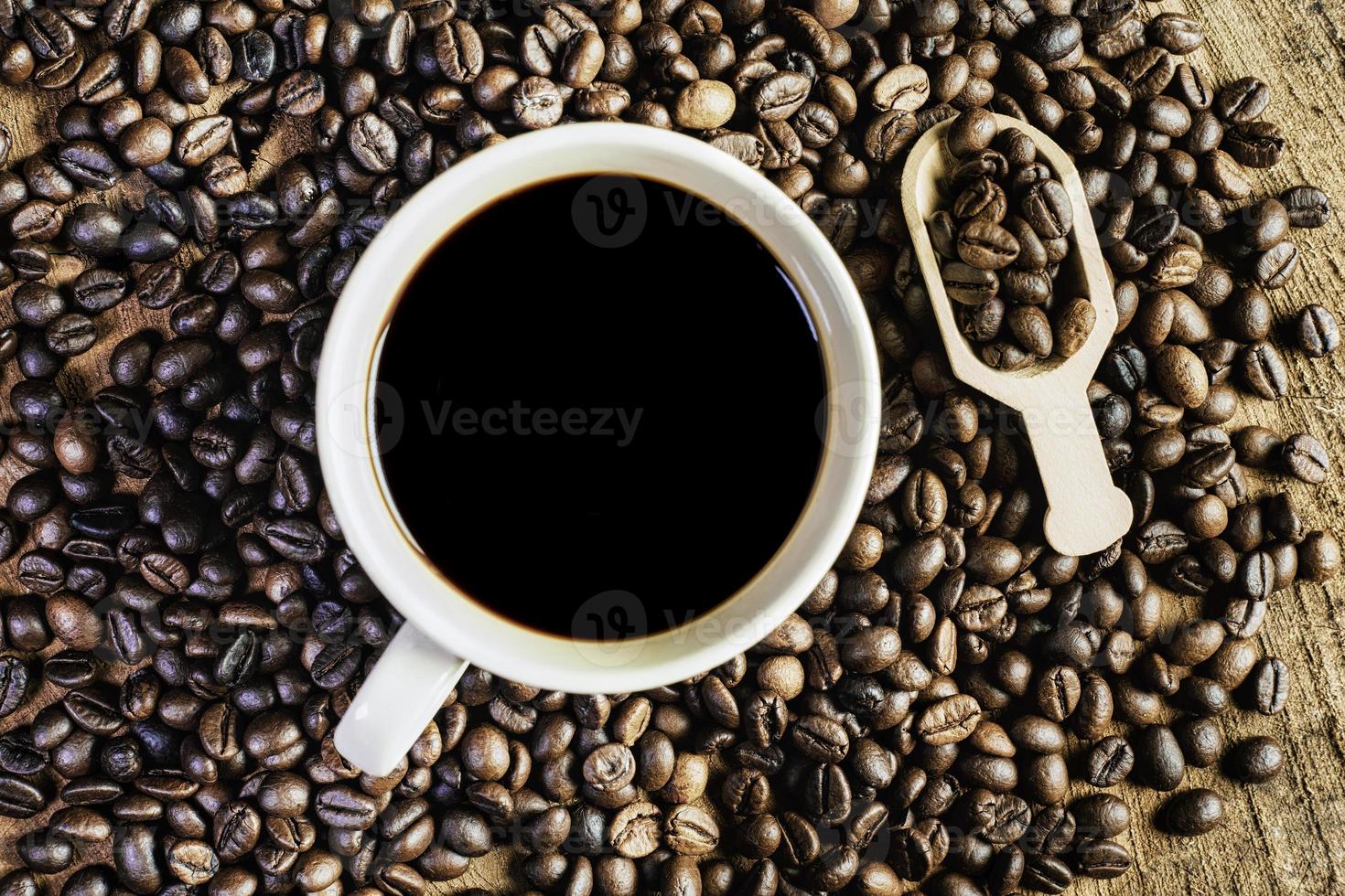 Black coffee in the cup, Dark Coffee beans on the old wooden floor,  Close up of seeds of coffee. photo