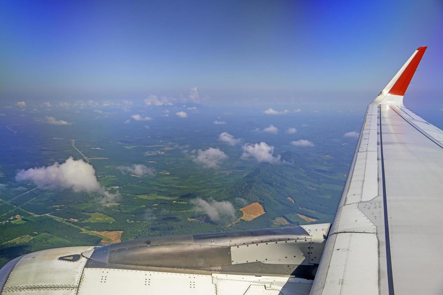 wings of airplanes during the flight look from the passenger window. There are white clouds in the blue sky. photo