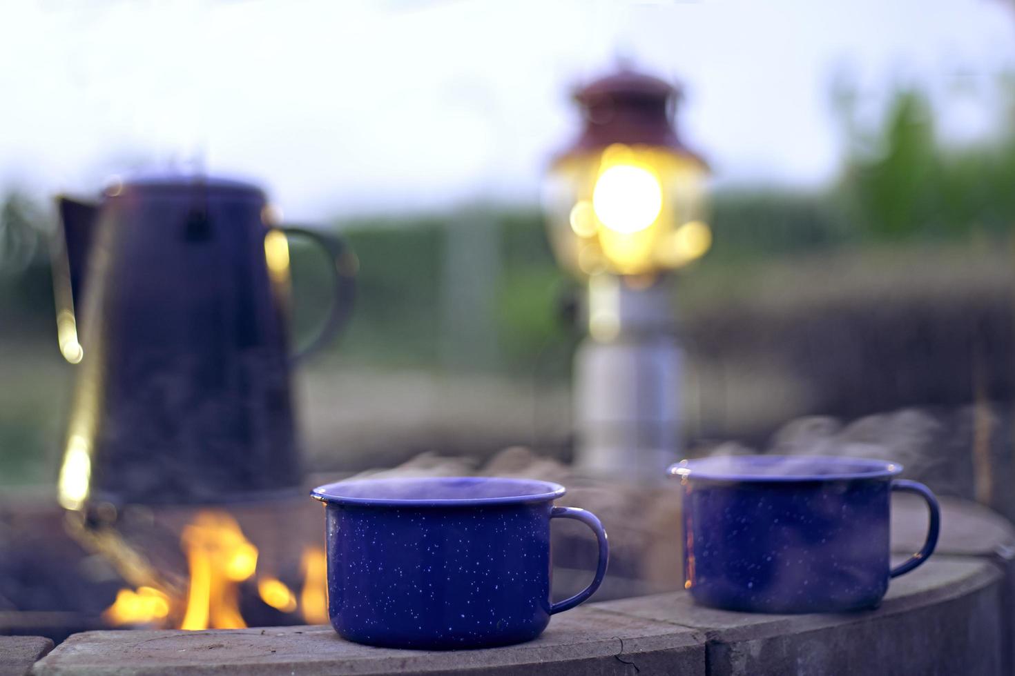 tetera de esmalte vintage en la estufa de leña en el campamento de la mañana. tetera de café antigua. hoguera en el campo.enfoque suave. foto