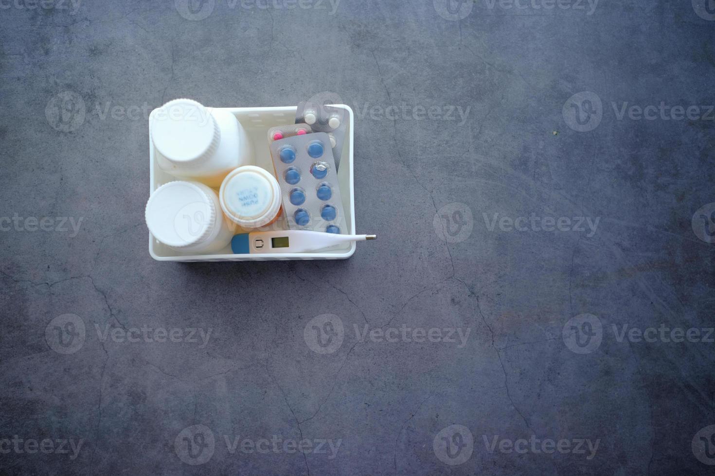 medical pill container, blister pack and thermometer in a plastic organizer photo