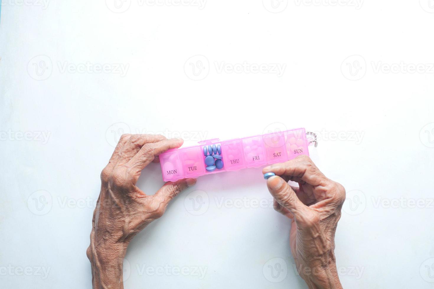 top view of senior women hands taking medicine from a pill box photo