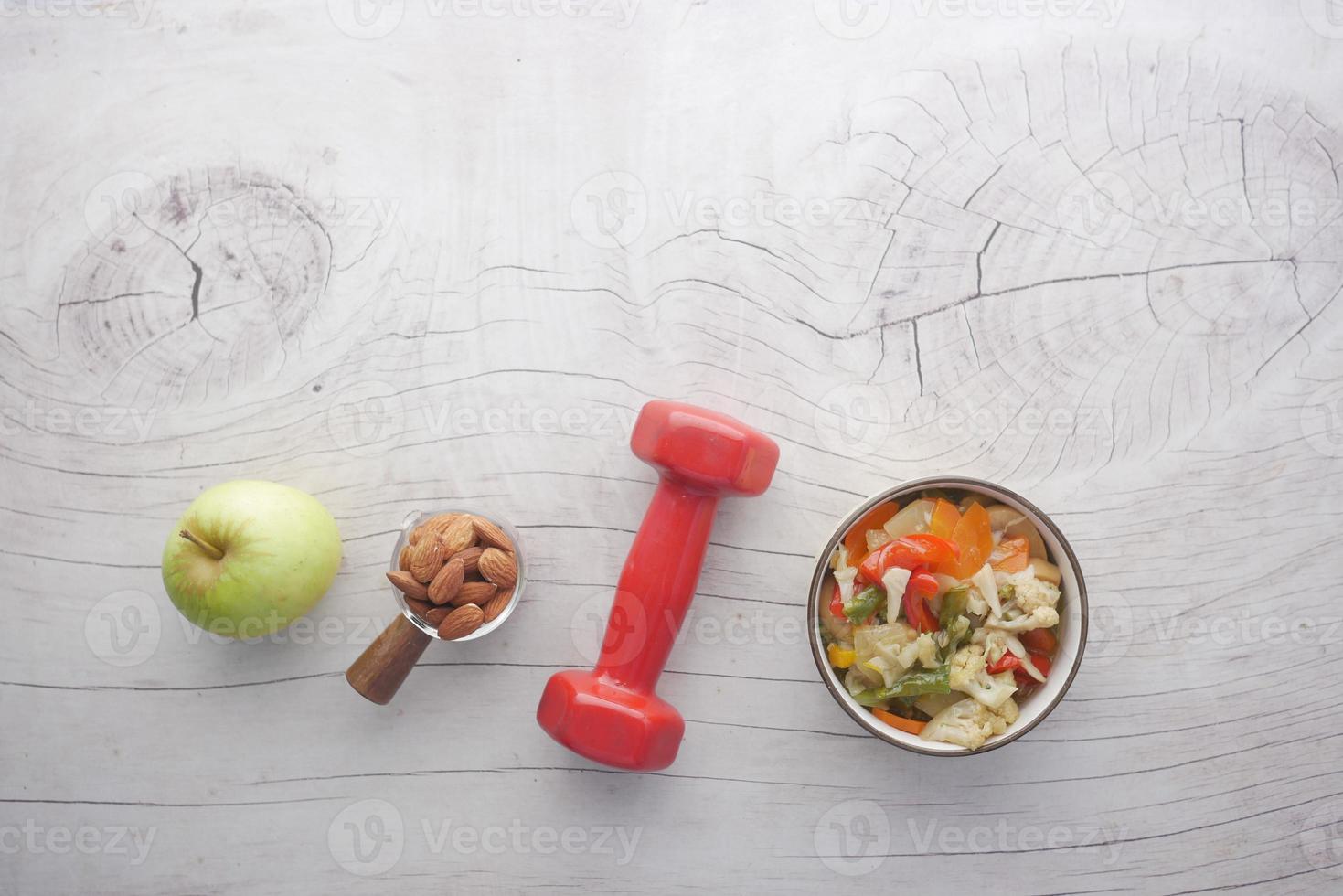 fresh salad, almond nut apple and dumbbell on table photo