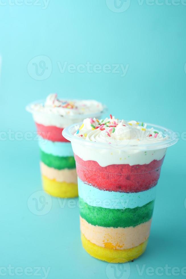 rainbow color cake in a plastic container on table photo