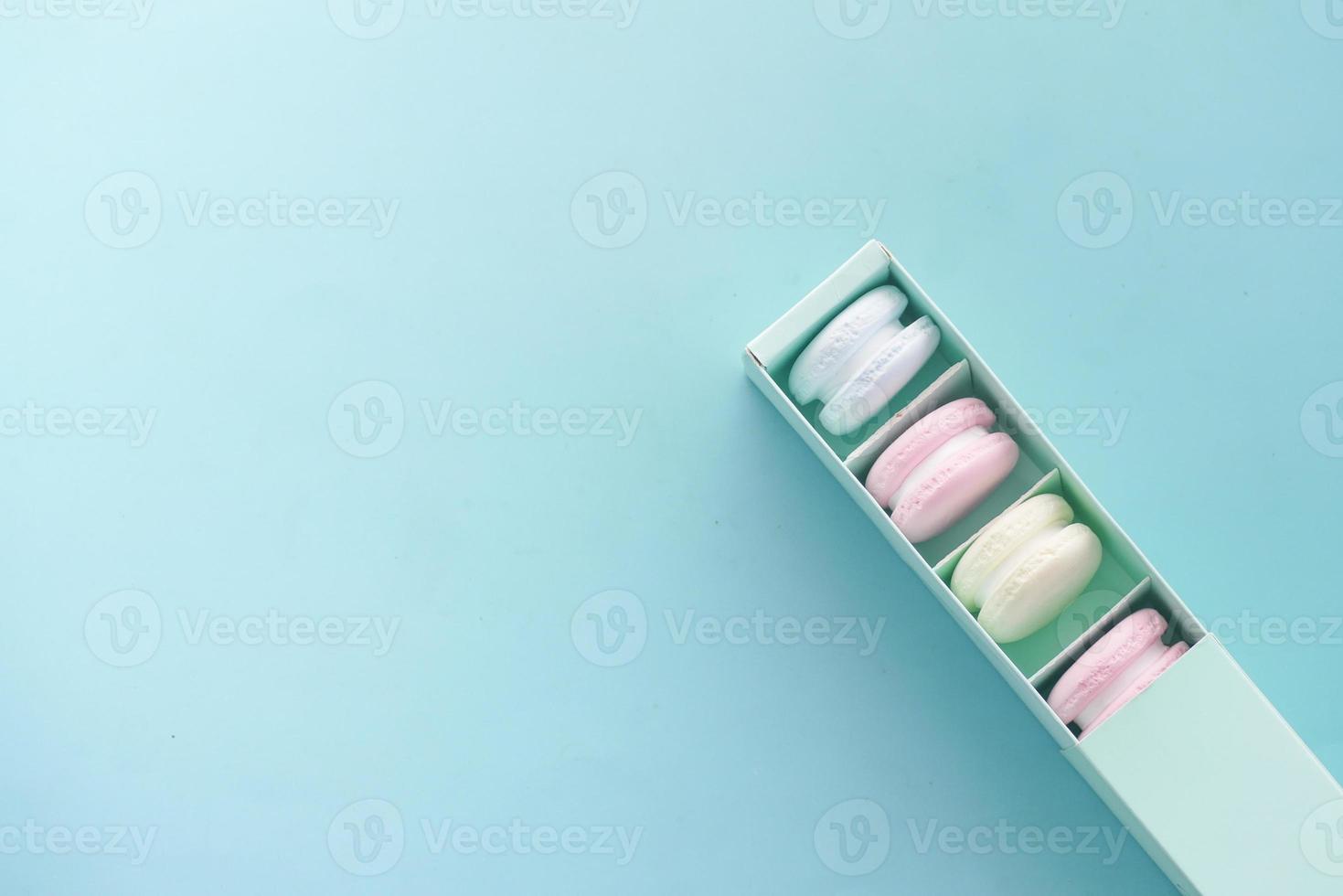macaroon in a paper box on light green background photo