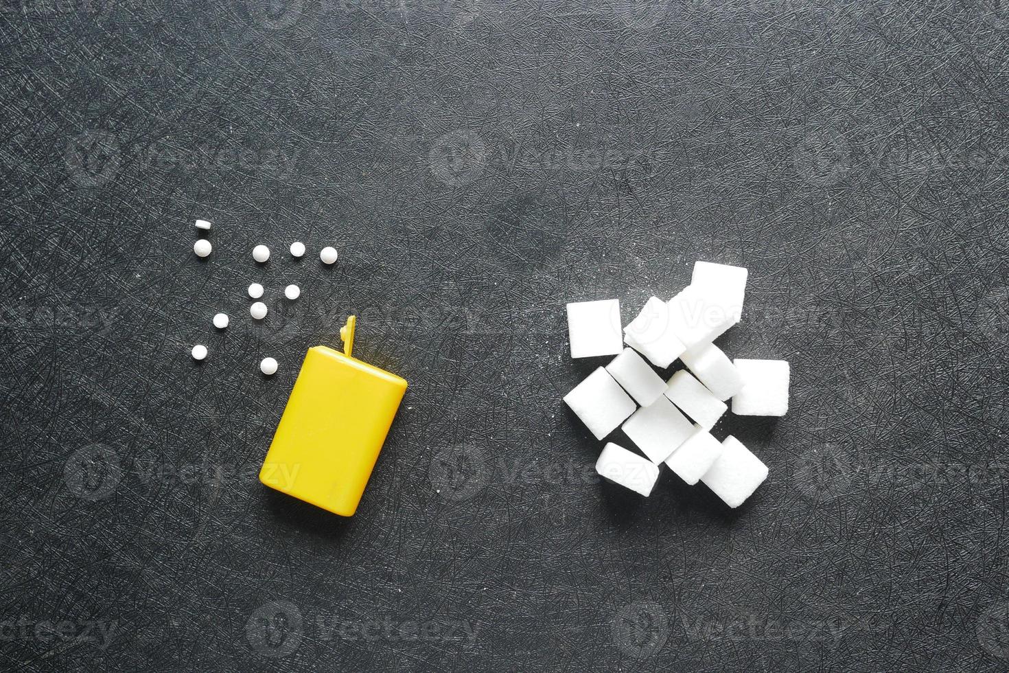 comparando edulcorante artificial con azúcar blanco sobre fondo negro foto