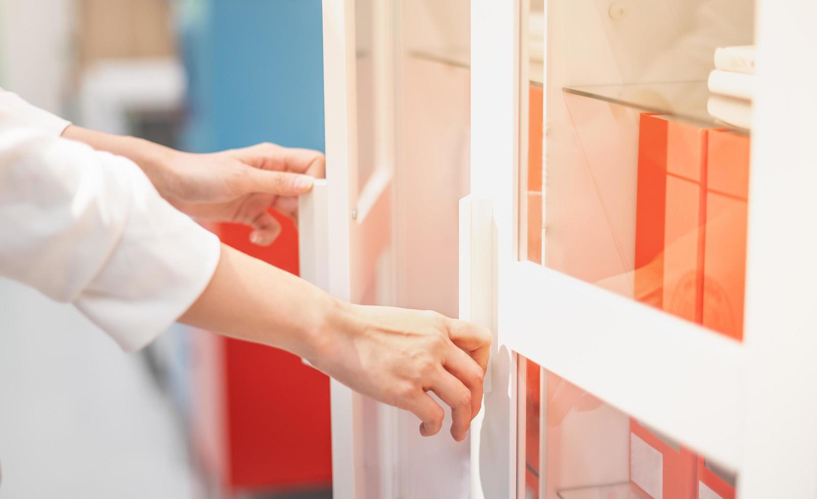 Female hand opening white document cupboard for choosing the document at the working office. photo