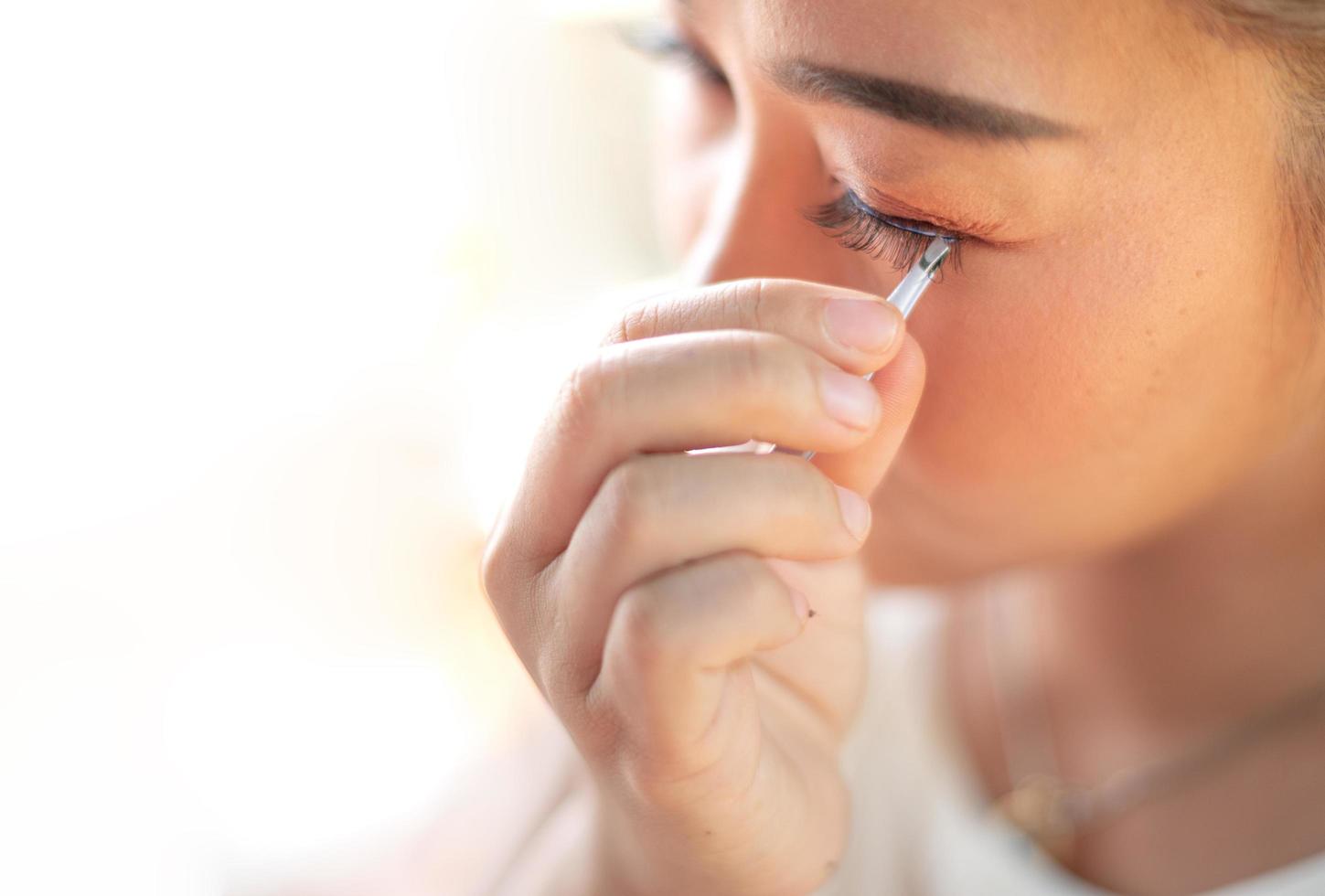 Female hand holding the eyelash and preparing attached to her eye. photo