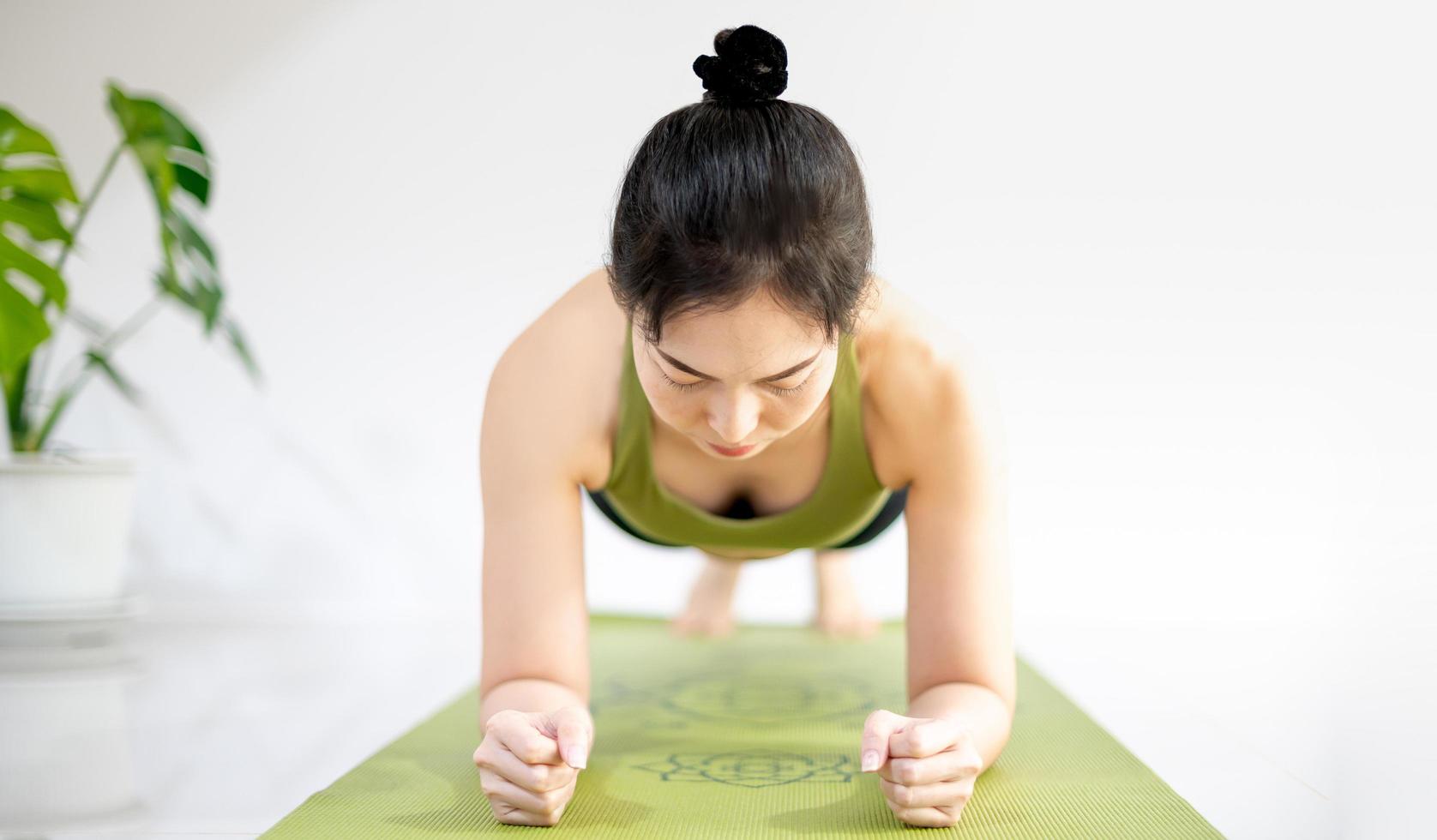 Woman doing yoga plank on the green yoga mat for meditate and exercise in the home. photo