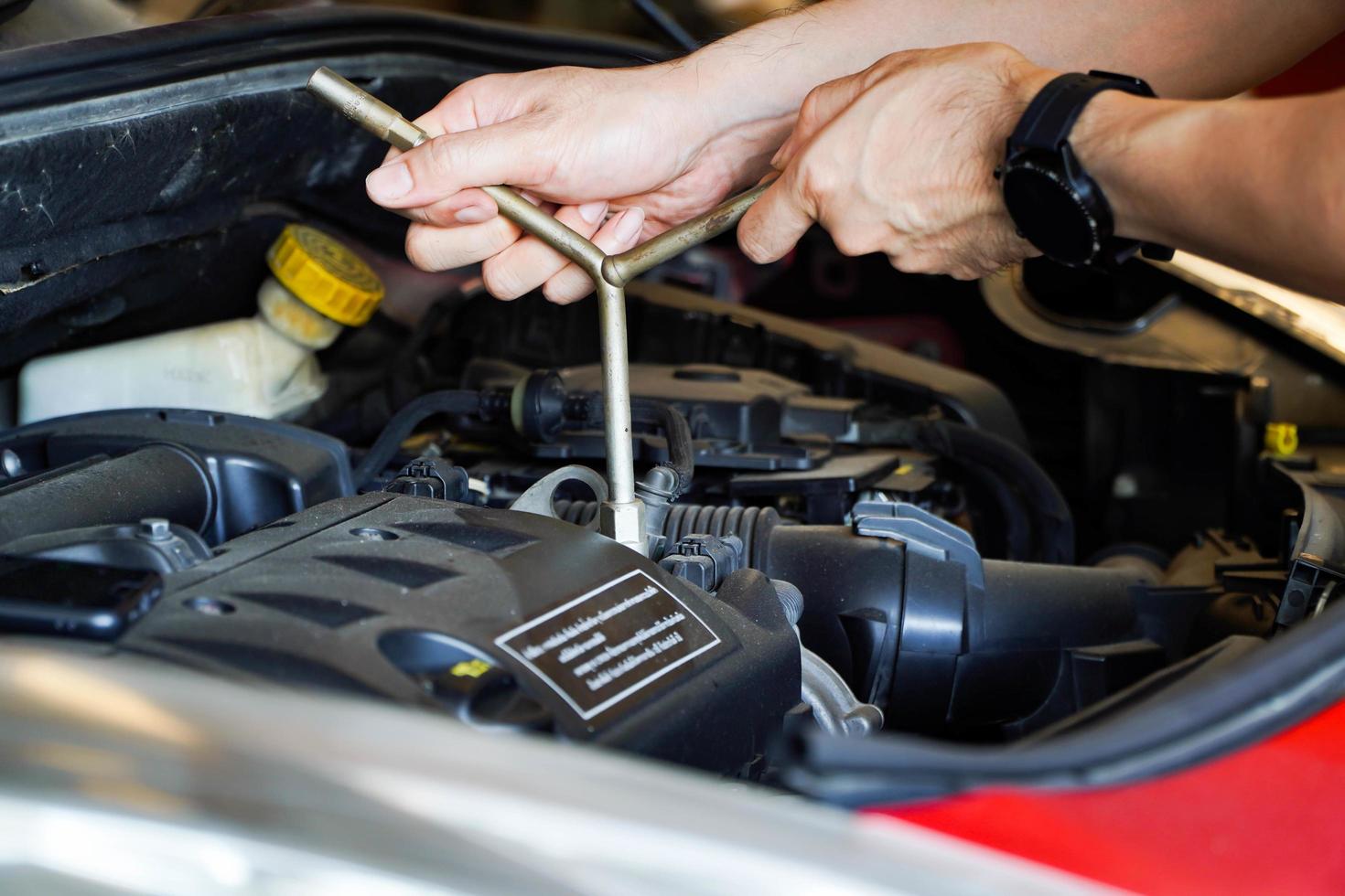 Mechanic works on the engine of the car in the garage. Repair service. Concept of car inspection service and car repair service. photo