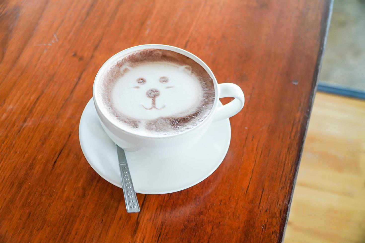Latte art in the shape of a bear on a coffee table on a wooden table. photo