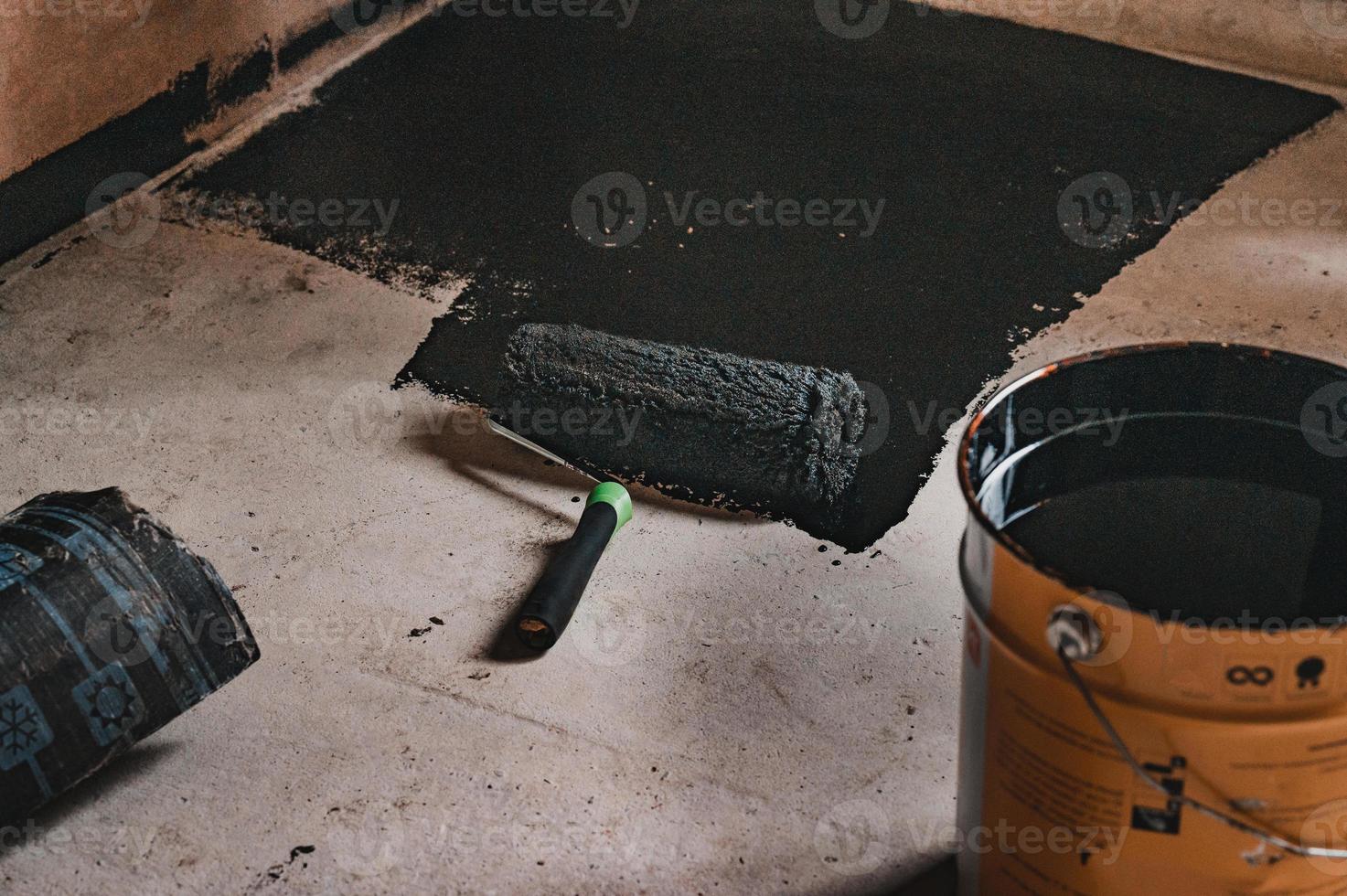 Aplicación de resina caliente al piso para impermeabilización, rodillo y balde de resina. foto