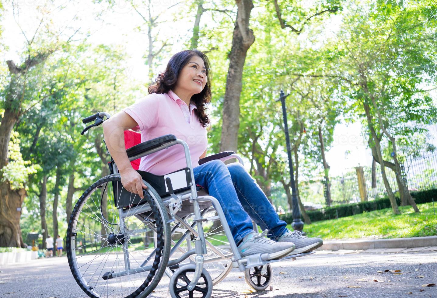 imagen de una mujer asiática de mediana edad sentada en silla de ruedas foto