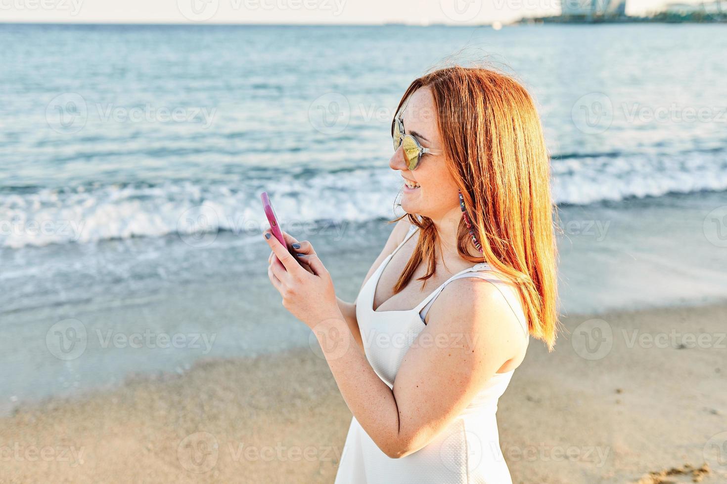 Red hair girl on the beach talking on the mobile photo