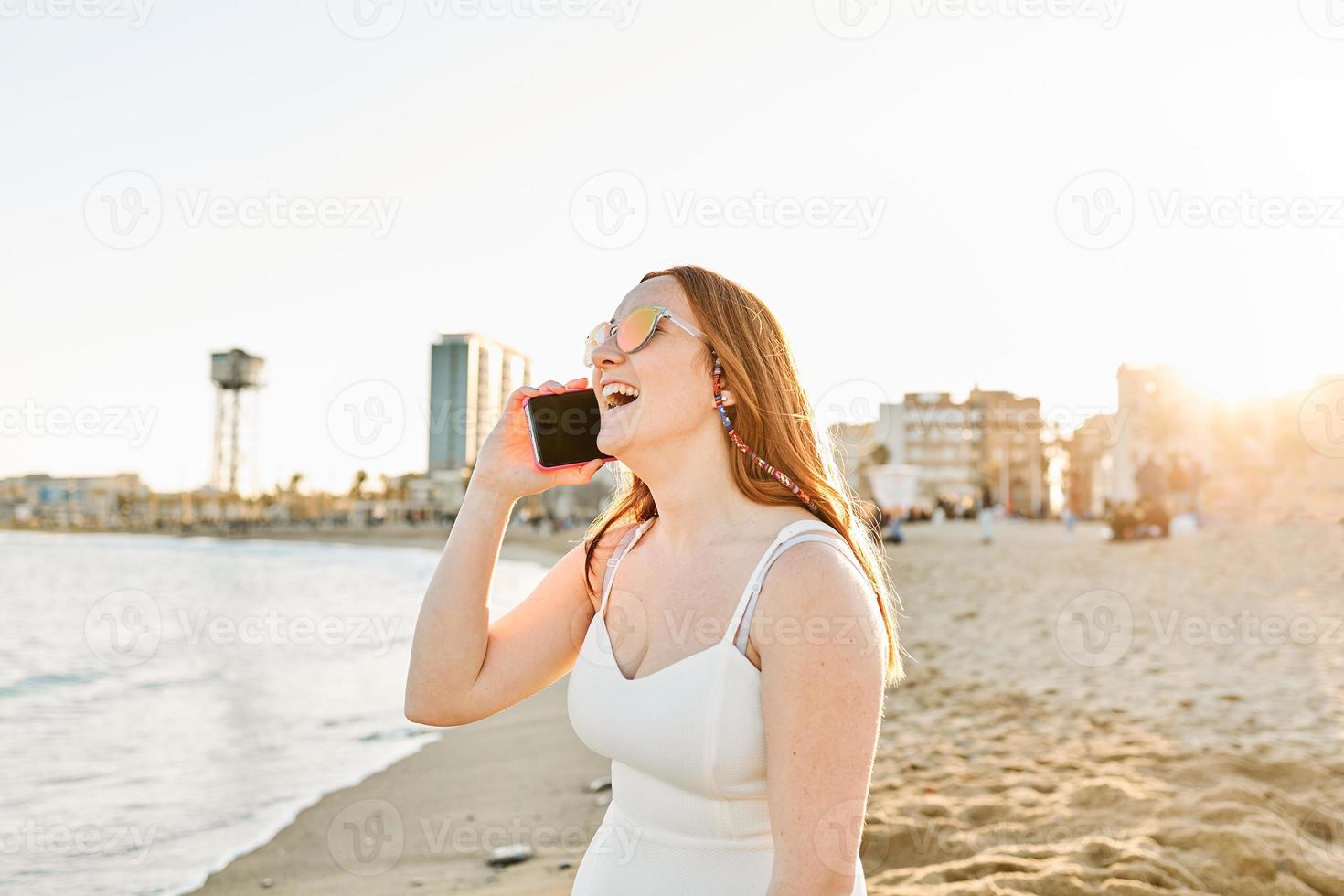 Red hair girl on the beach talking on the mobile photo
