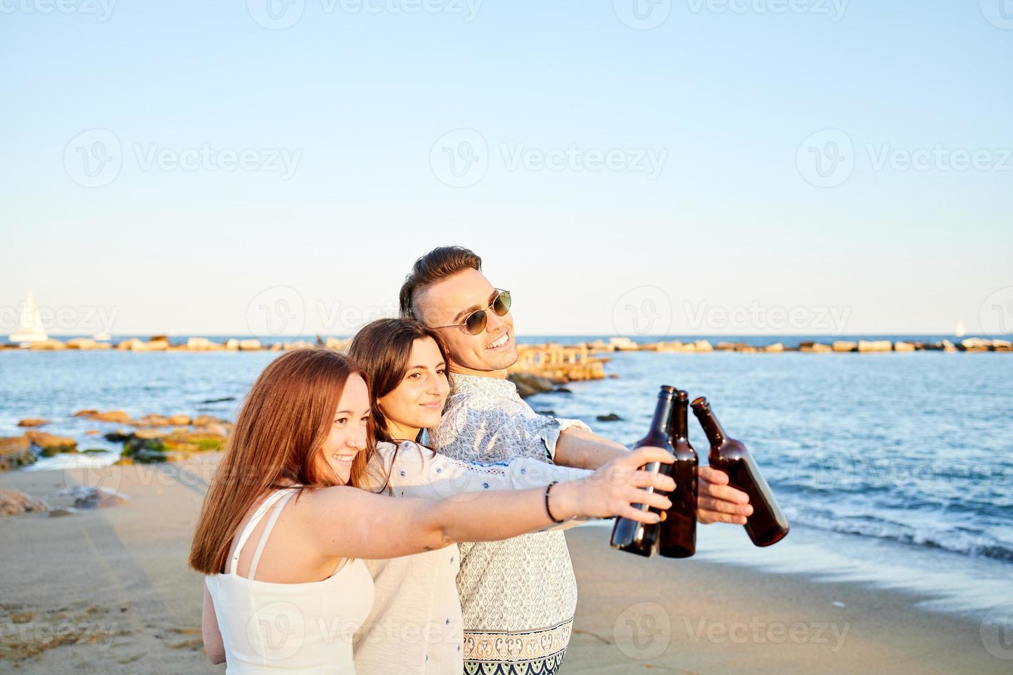 Friends drinking beer on the beach photo